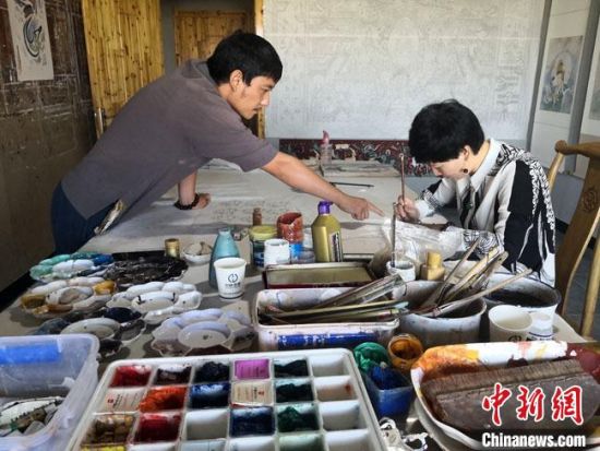 圖為2020年8月下旬，敦煌“80后”畫家張杰龍(左)在為云南麗江“學(xué)生”莫北講解敦煌壁畫的繪畫技巧?！●T志軍 攝