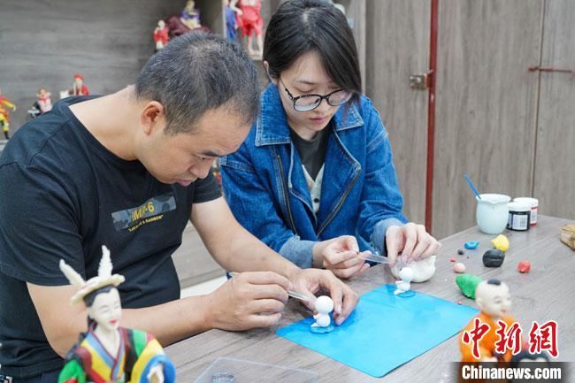 <a target='_blank'  data-cke-saved- >中新社</a>記者(右)現(xiàn)場體驗面塑制作過程?！￡悹帍?攝