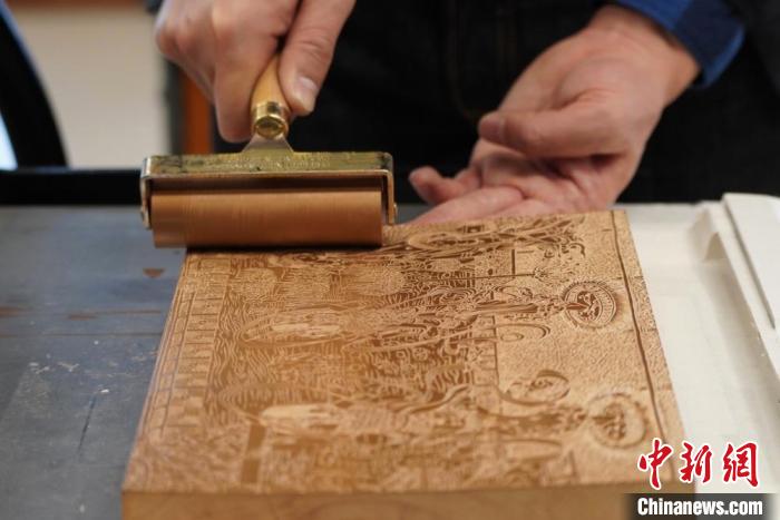 圖為徐晉林工作室工作人員正在給雕好壁畫的版面滾油墨?！【琶赖┰?　攝