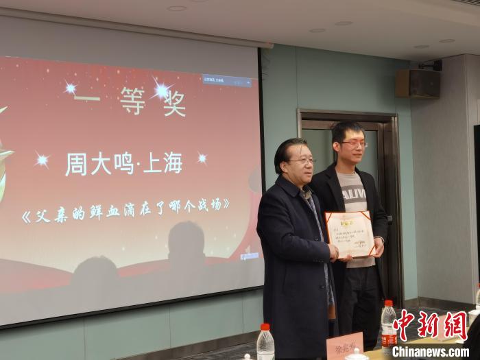 圖為作家、西北師范大學(xué)新聞與傳媒學(xué)院院長(zhǎng)徐兆壽頒發(fā)一等獎(jiǎng)證書(shū)，代領(lǐng)獎(jiǎng)?wù)呱吓_(tái)領(lǐng)獎(jiǎng)?！钅?攝