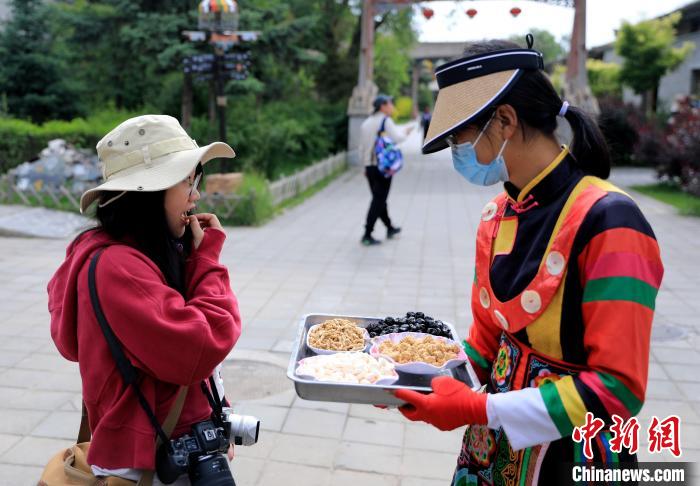 圖為身穿土族服飾的女性介紹當(dāng)?shù)靥厣〕??！⊙Φ?攝