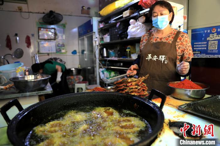 圖為平安驛·河湟民俗文化體驗(yàn)地內(nèi)的商戶炸干板魚?！⊙Φ?攝