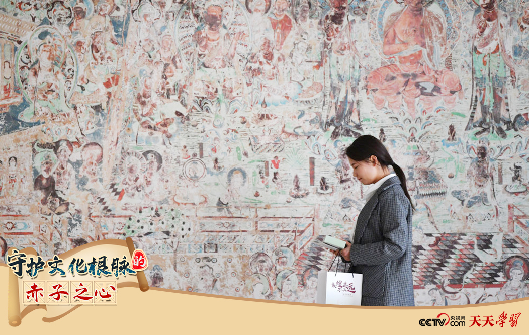 2023年4月25日，敦煌研究院文物數(shù)字化保護(hù)團(tuán)隊(duì)創(chuàng)意營銷人員廖雪婷從一幅高保真復(fù)制壁畫前走過。