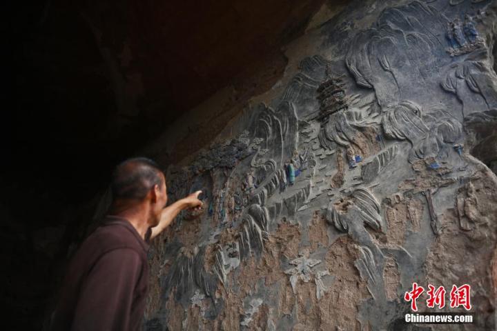 7月15日，甘肅省平?jīng)鍪袥艽h百里石窟長廊羅漢洞石窟內(nèi)，該窟文保員郭建平介紹窟內(nèi)石刻彩繪壁畫。郭建平家中三代人曾自發(fā)保護(hù)羅漢洞石窟。羅漢洞石窟遺存40余個窟龕，以北魏至清代風(fēng)格為主。中新社記者 李亞龍 攝