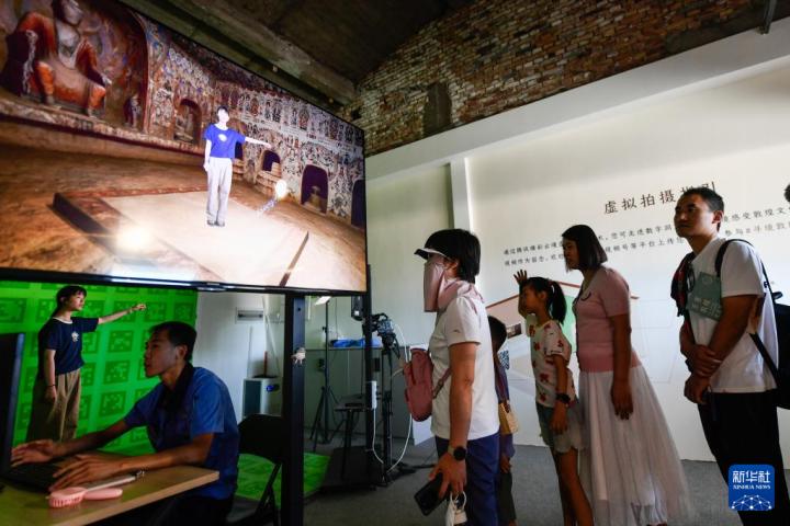 7月22日，游客體驗“尋境敦煌——數(shù)字敦煌沉浸展”后，在虛擬演播廳拍攝一段真人與洞窟虛擬場景交互的視頻。新華社記者 郎兵兵 攝</p>
<p>