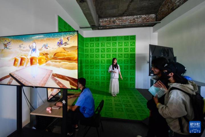 7月22日，游客體驗“尋境敦煌——數(shù)字敦煌沉浸展”后，在虛擬演播廳拍攝一段真人與洞窟虛擬場景交互的視頻。新華社記者 郎兵兵 攝</p>
<p>